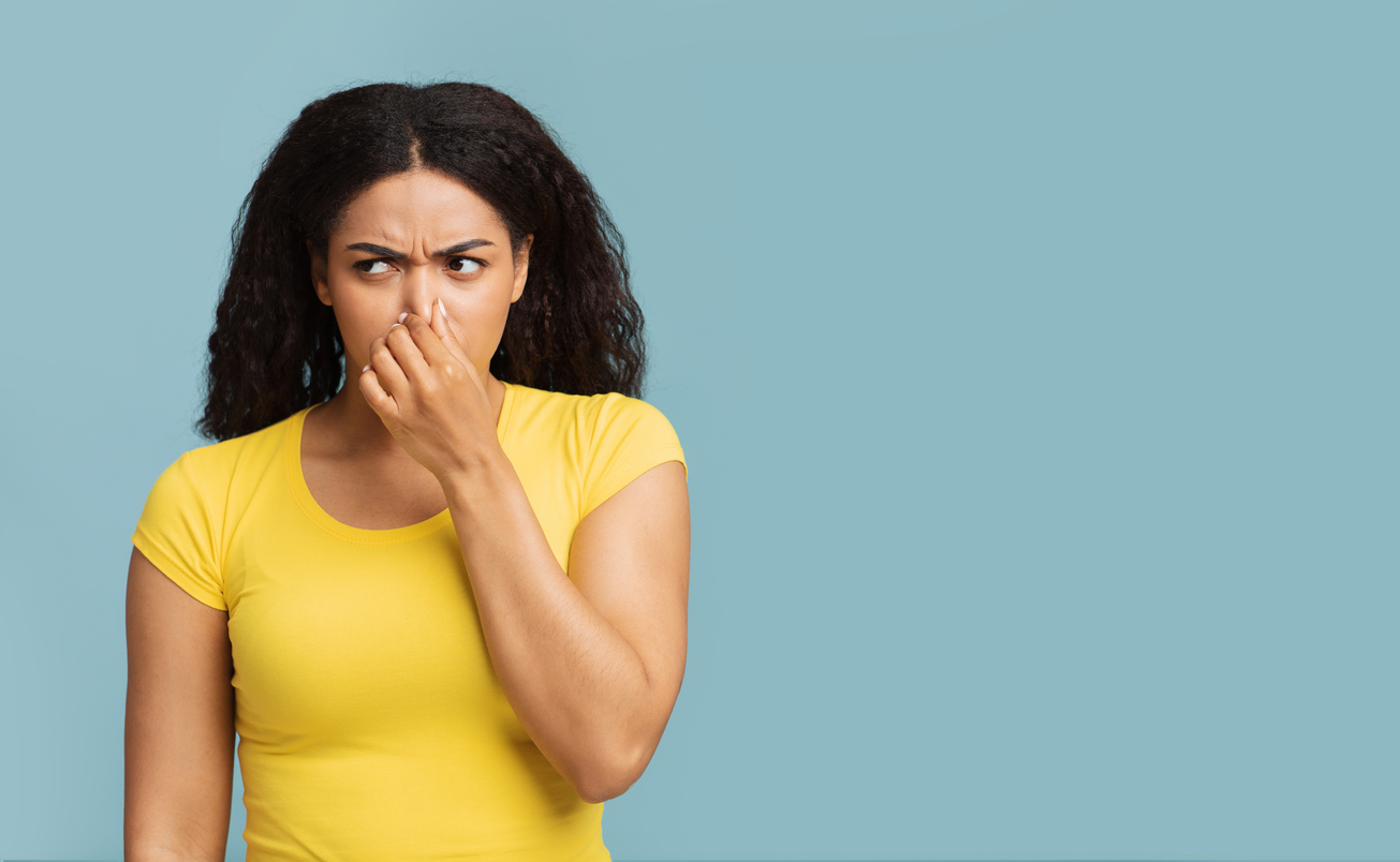woman covering her nose from bad smelling fart